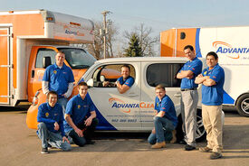Employees posing in front of company car