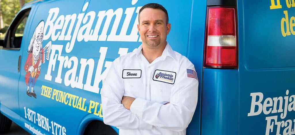 Plumbing Technician smiling in front of van