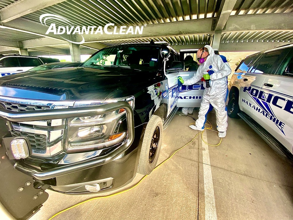 Employee cleaning a car in hazmat suit